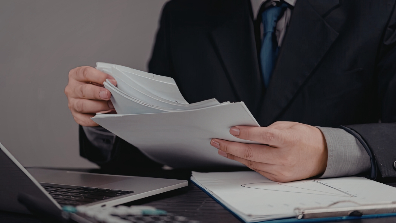 Paušalac pregleda dokumenta za stolom pored laptopa